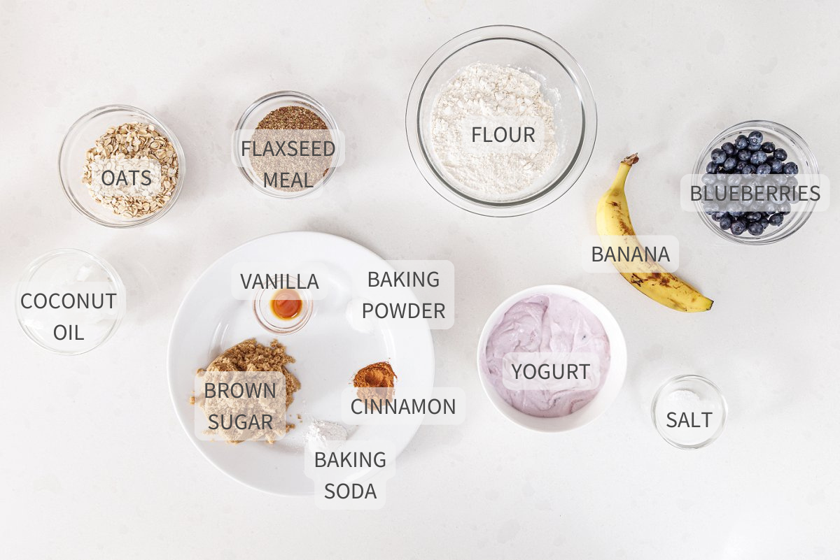 Labeled ingredients for blueberry banana flaxseed muffins on white counter.