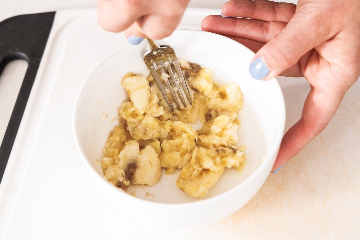 Mashing banana with a fork in a bowl.