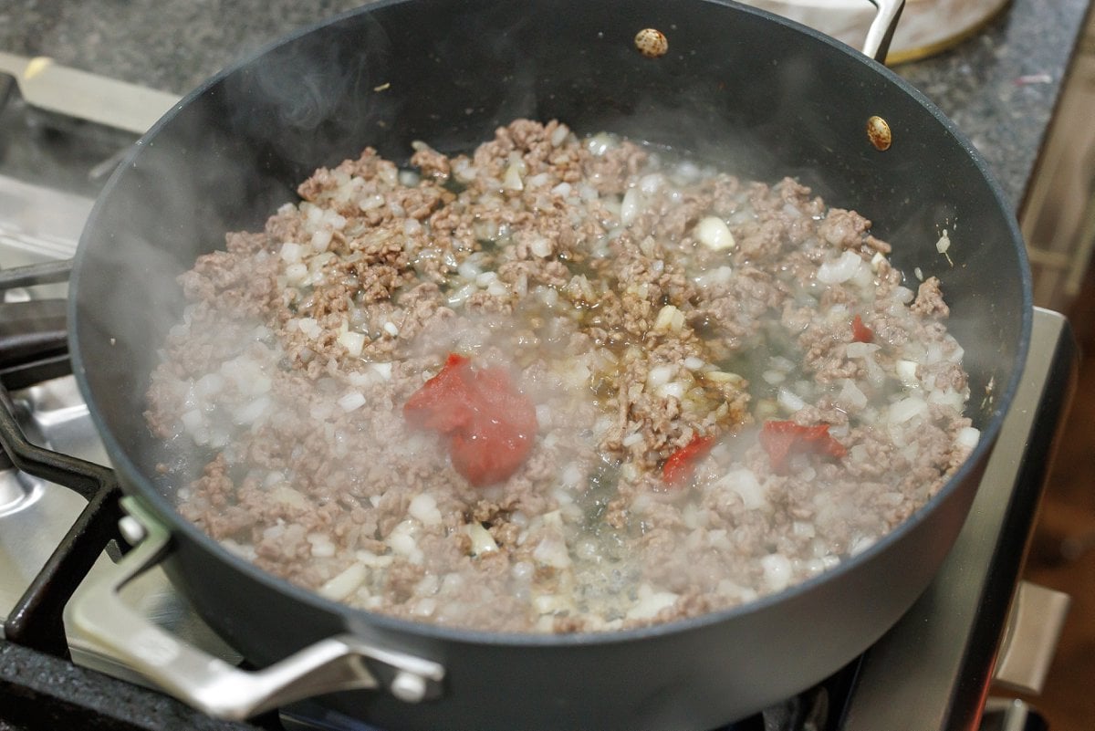 Adding tomato paste to ground lamb mixture.