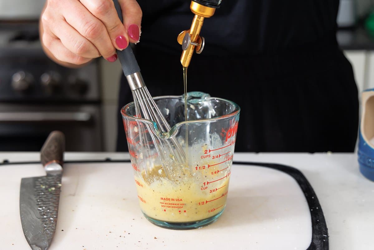 Whisking olive oil into maple dijon marinade.