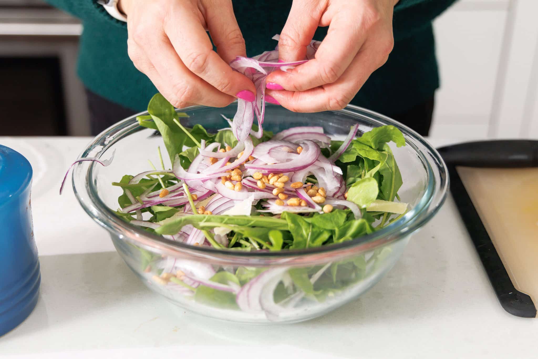 Adding thinly sliced red onions to Italian mixed saald.