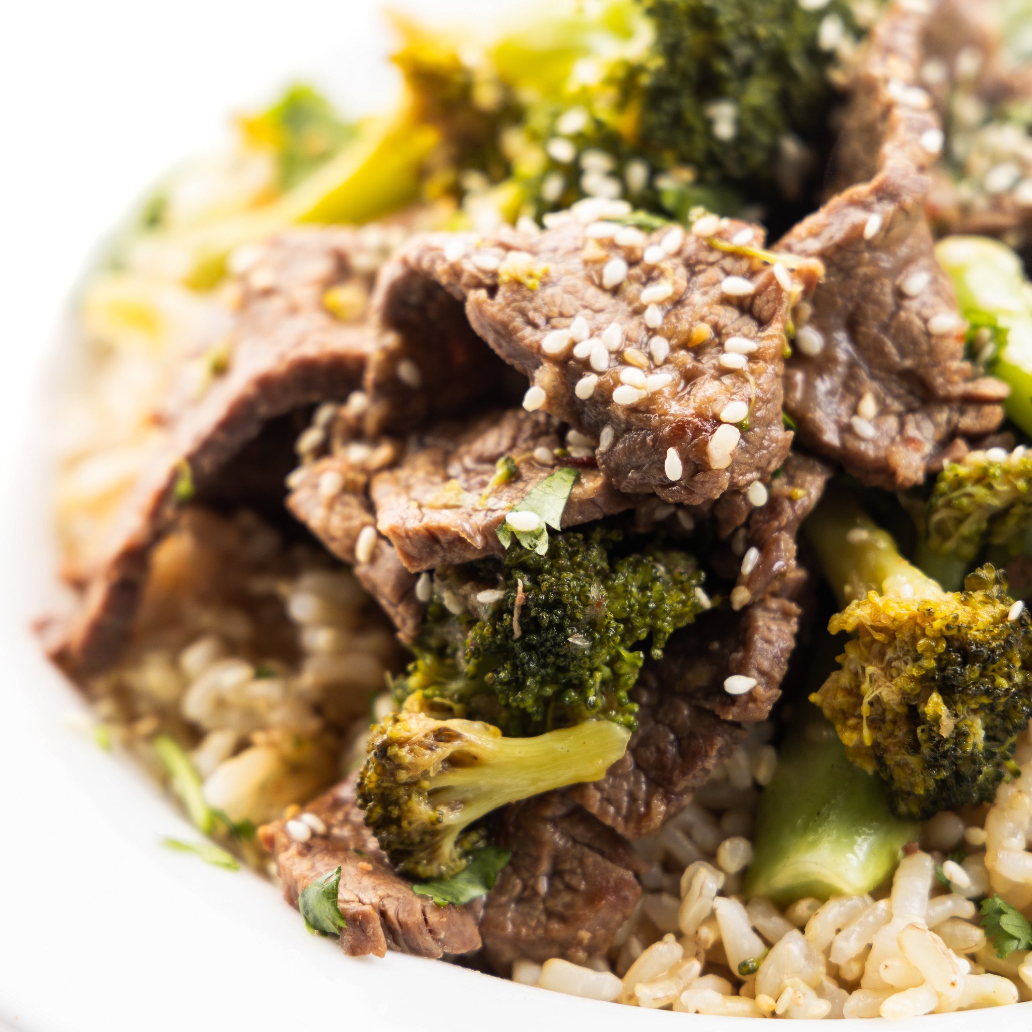 Beef and broccoli stir-fry over brown rice and topped with sesame seeds.