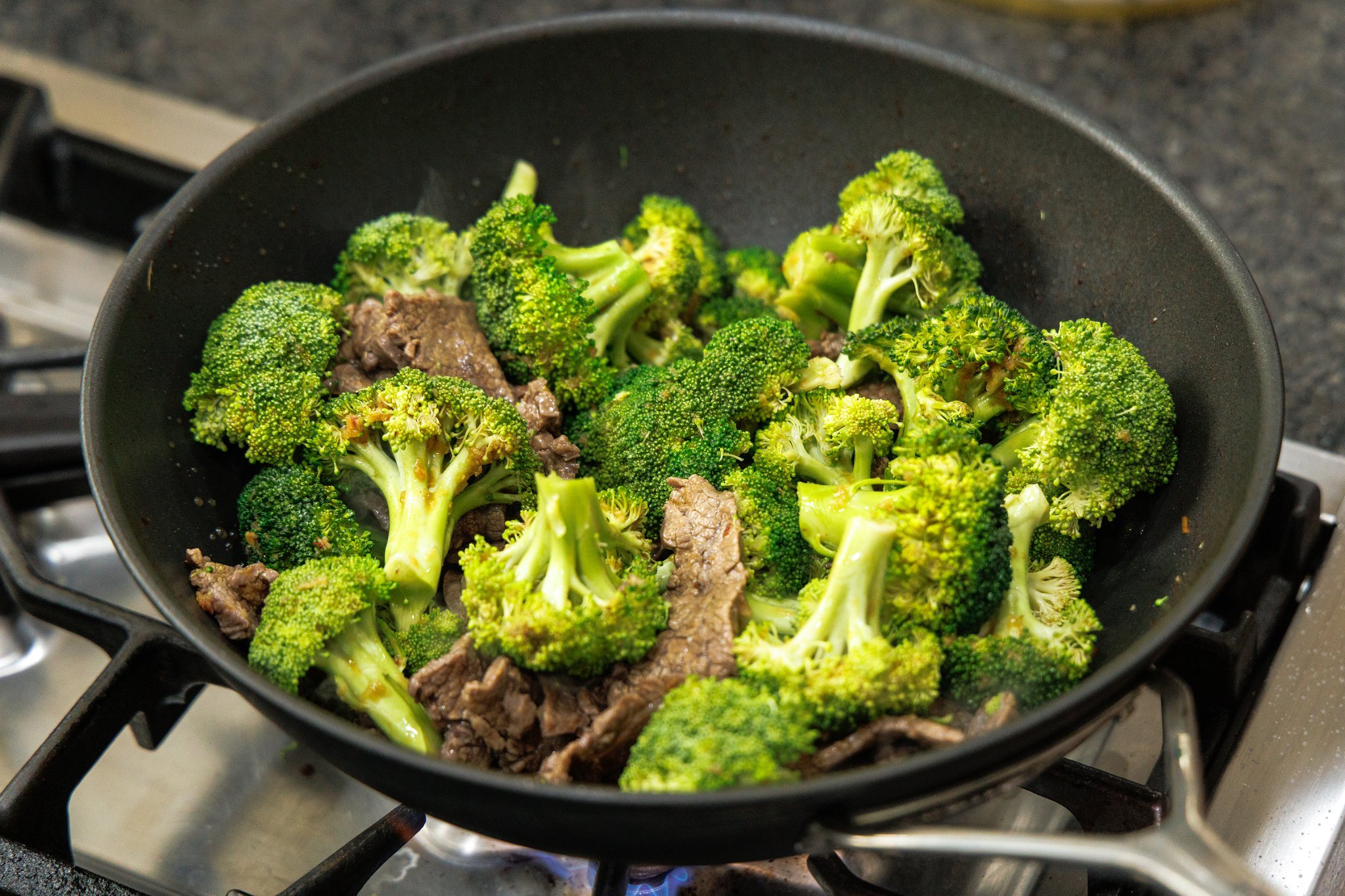 Cooking beef and broccoli stir-fry in wok.