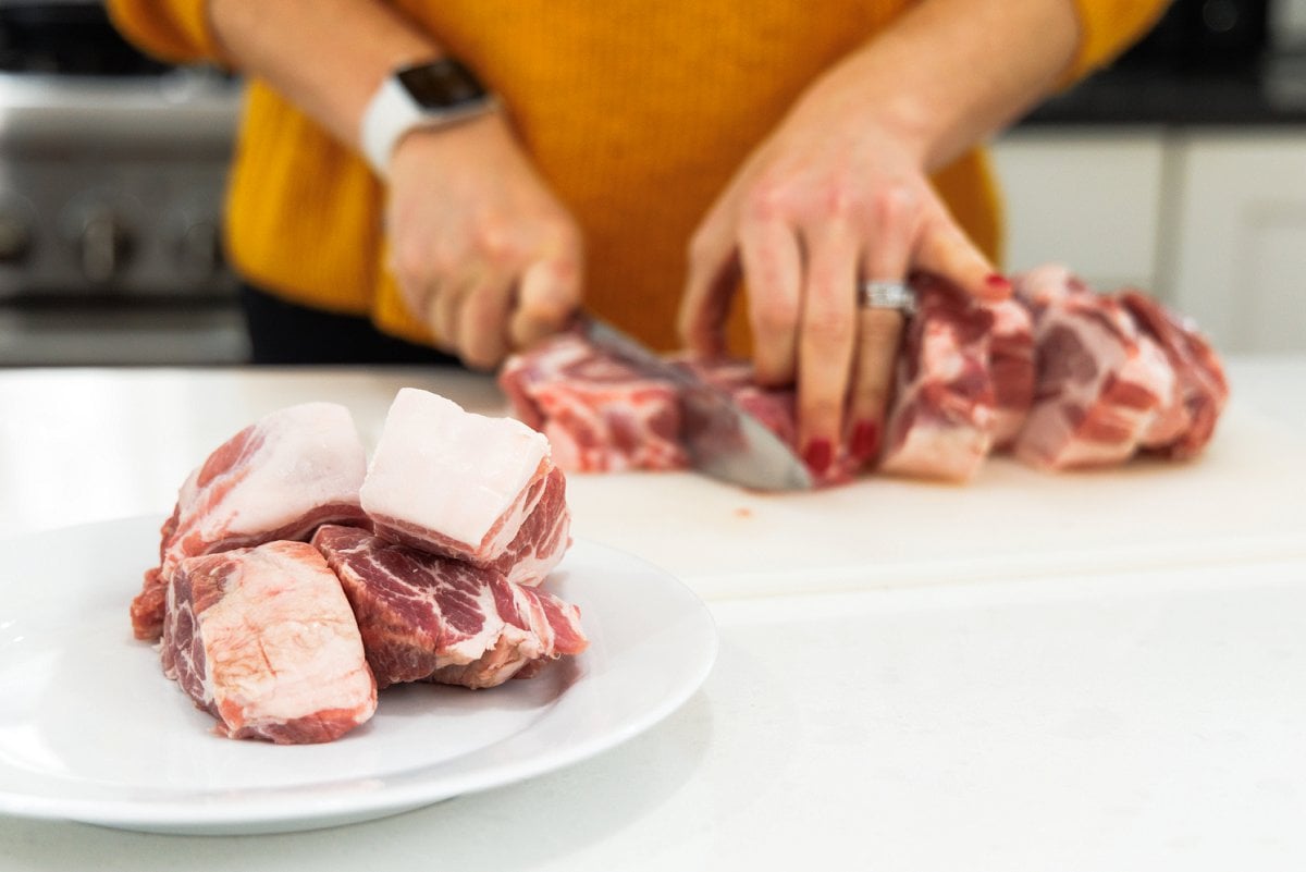 Cutting pork roast into smaller chunks.